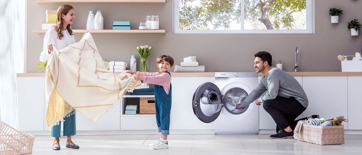 Rodzina z dzieckiem wyjmują pranie z pralki 