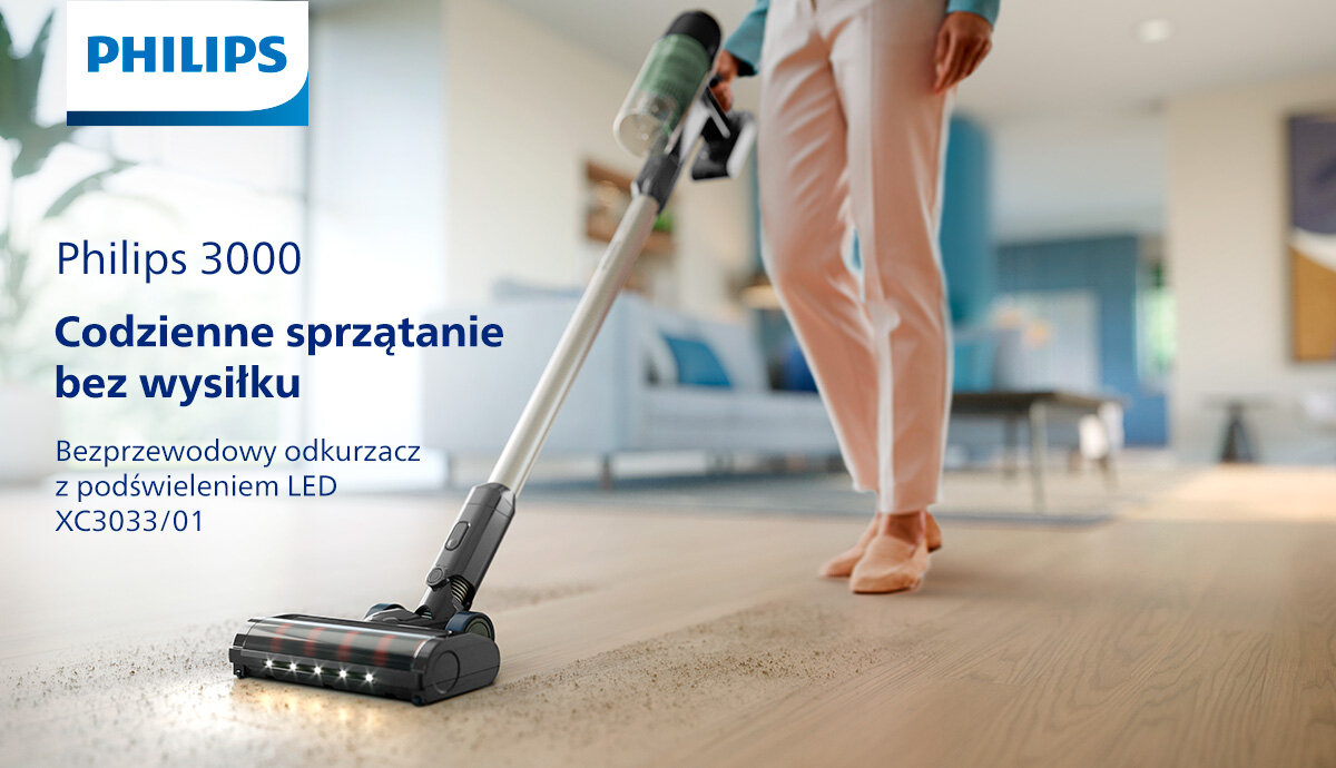 Osoba używa bezprzewodowego odkurzacza na drewnianej podłodze w jasnym wnętrzu. Widoczny tekst: \'Philips 3000 Codzienne sprzątanie bez wysiłku Bezprzewodowy odkurzacz z podświetleniem LED XC3033/01\'.