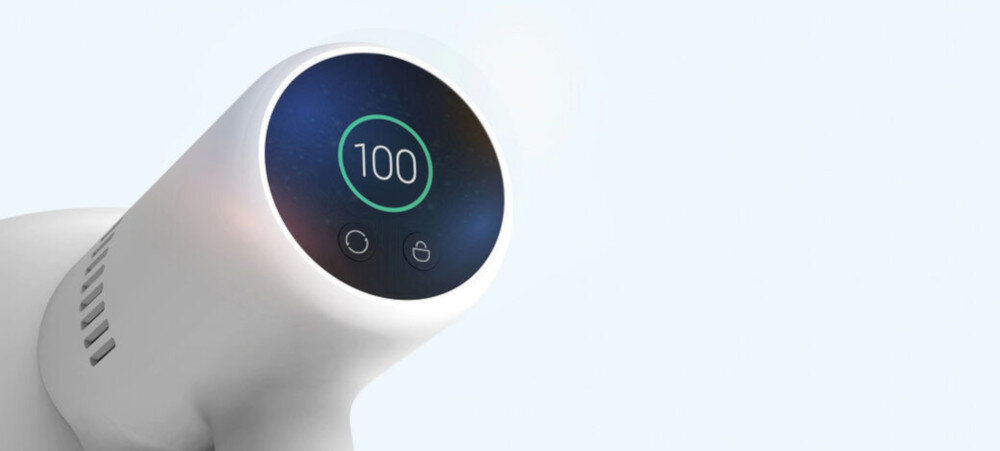 Biały odkurzacz z okrągłym wyświetlaczem pokazującym liczbę 100 oraz dwa ikony poniżej. Tło jest jasne i jednolite.