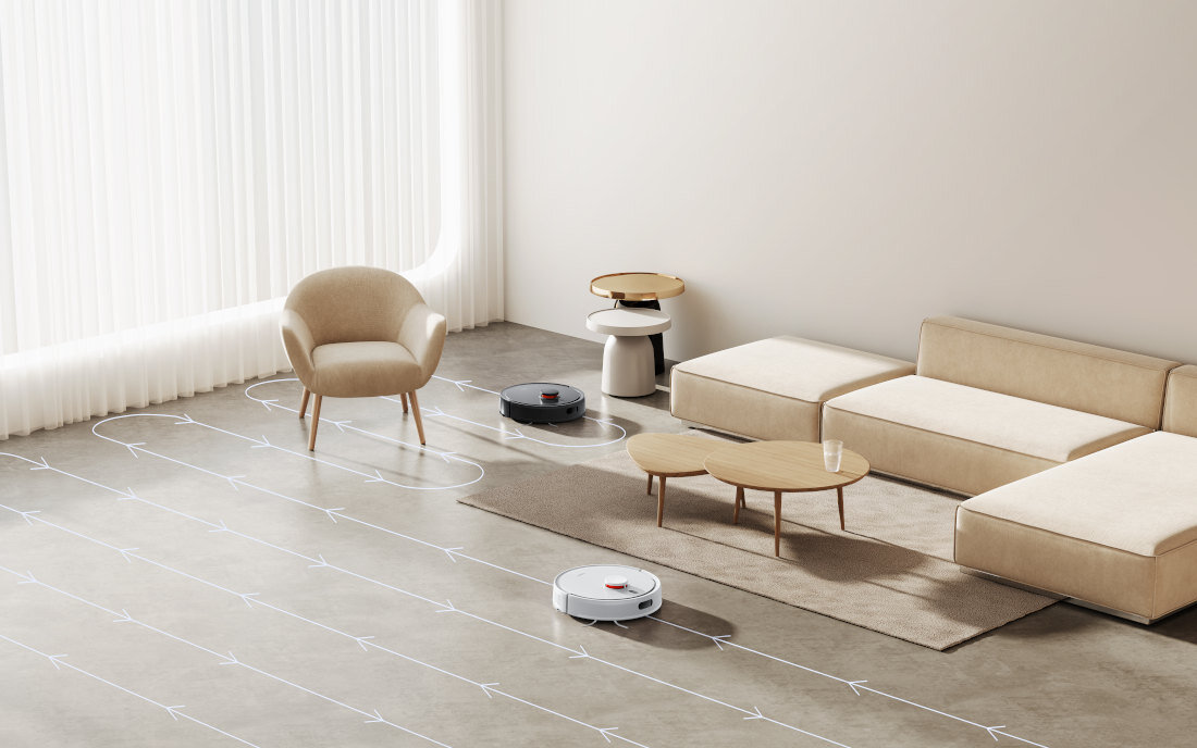 W nowoczesnym salonie znajdują się dwa roboty sprzątające na podłodze, jeden czarny i jeden biały. W pomieszczeniu są także beżowe meble, w tym sofa, fotel i stolik kawowy.