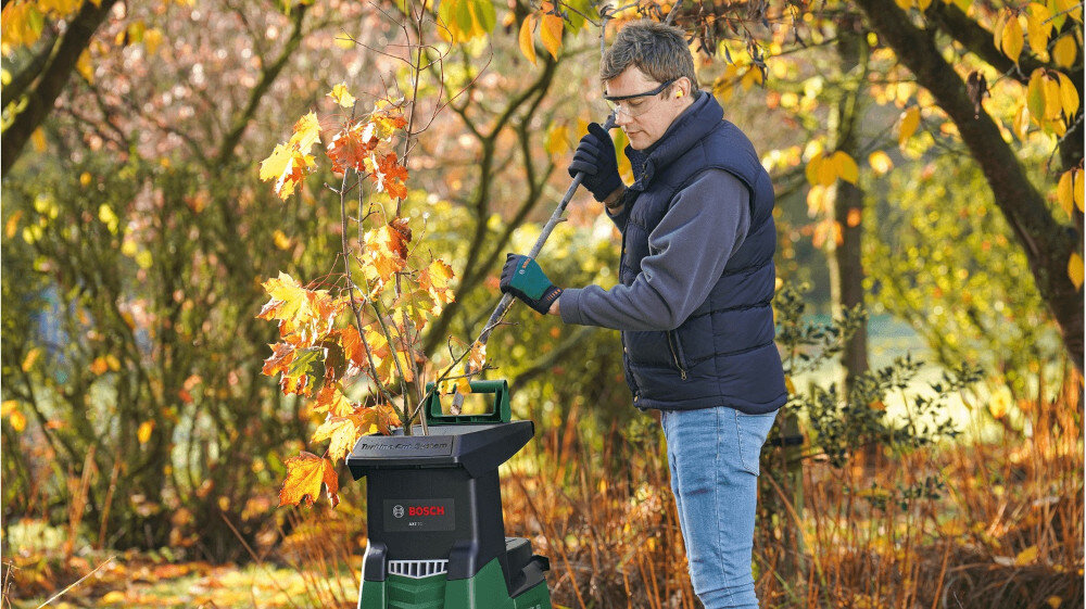 Rozdrabniacz do gałęzi BOSCH AXT 25 TC elektryczny 2500 W sekator + rękawice ogród sad drzewa liście osoba upycha w rozdrabniaczu gałęzie porządek mobilność rozdrabnianie odpadków