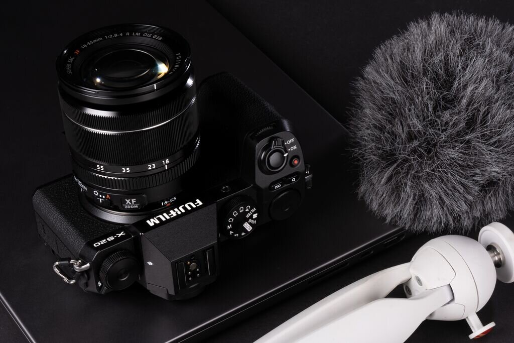 Aparat FUJIFILM X-S20 na blacie obok mikrofonu i statywu  