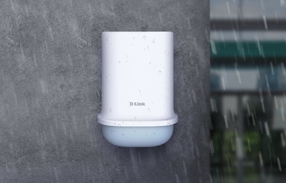 Na obrazie widoczny jest biały, cylindryczny router z logo \'D-Link\' na szarej ścianie. Na urządzeniu znajdują się krople wody, a w tle widać rozmyty budynek i padający deszcz.