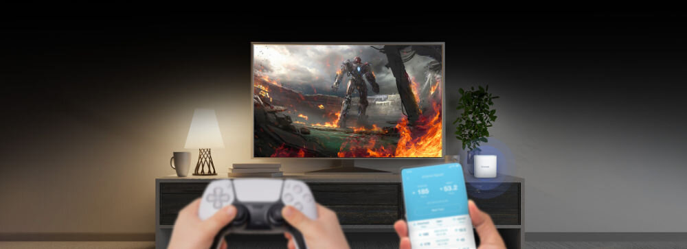 Na obrazie widać telewizor wyświetlający scenę z gry wideo z postacią w zbroi na tle ognia. Przed telewizorem znajdują się ręce trzymające kontroler do gier i smartfon z widocznym interfejsem aplikacji.