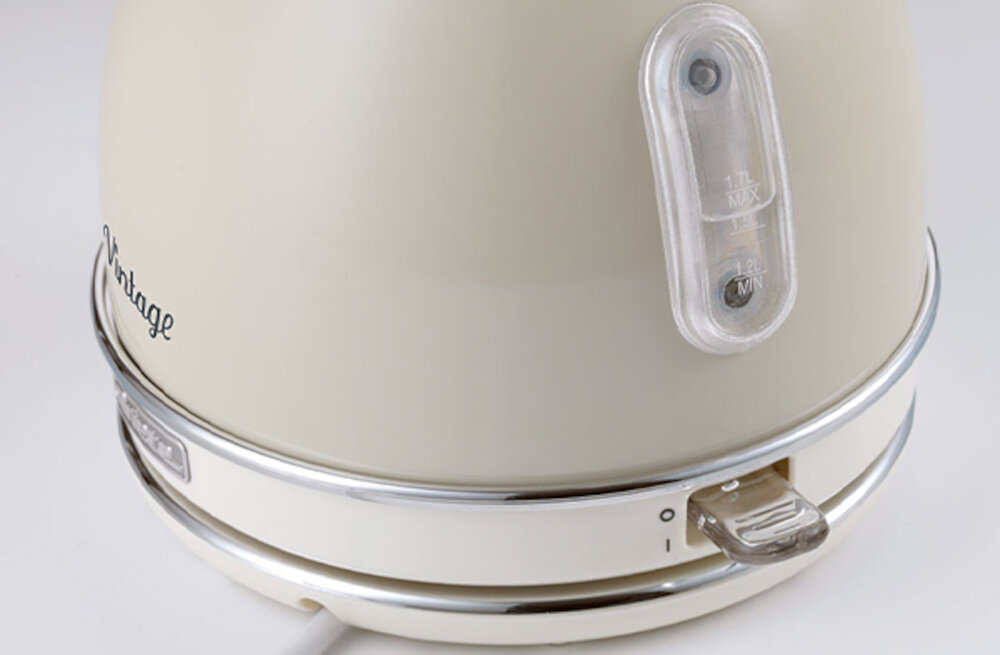 Beżowy czajnik z napisem \'Vintage\' i wskaźnikiem poziomu wody z oznaczeniami \'1.7L MAX\' i \'1.2L MIN\'. Czajnik posiada chromowane wykończenia i przełącznik z oznaczeniami włącz/wyłącz.