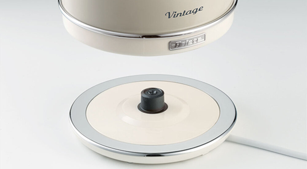 Na obrazie widoczna jest podstawka czajnika w kolorze kremowym z metalicznym wykończeniem. Na czajniku znajduje się napis \'Vintage\' oraz logo \'Ariete\'.