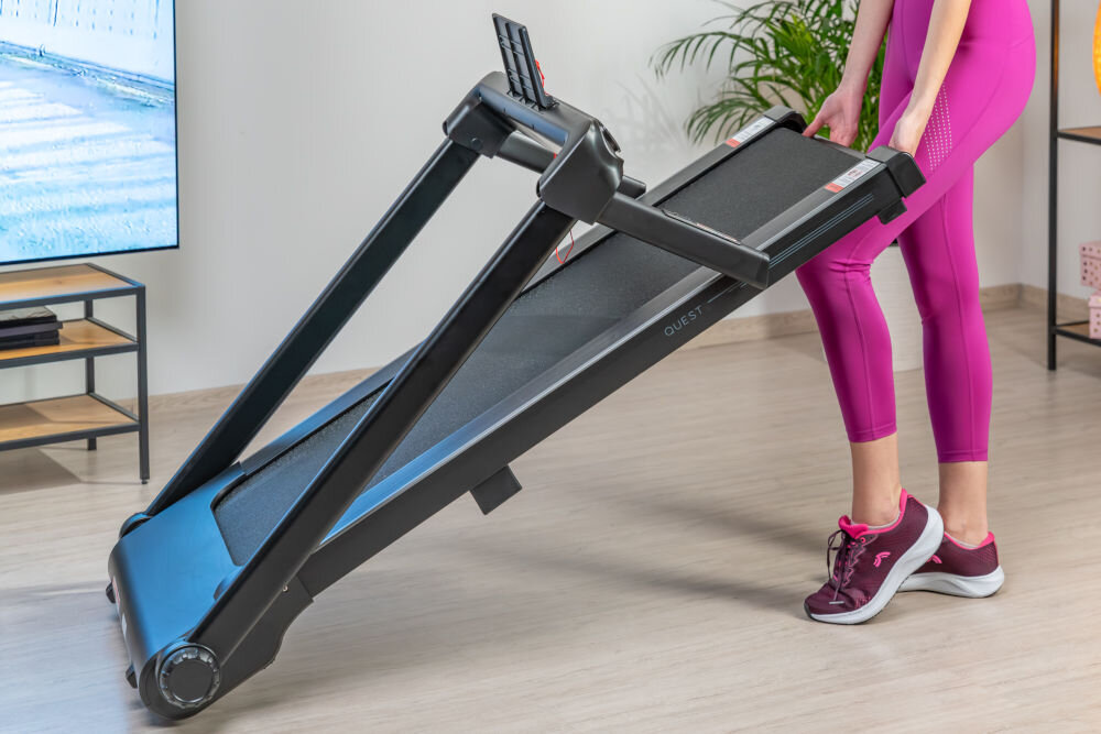 Bieżnia elektryczna S-LINE Quest 1490W 12km/h osoba trzymająca bieżnię składania kompaktowe wymiary niewielki rozmiar lekka waga około 44 kg