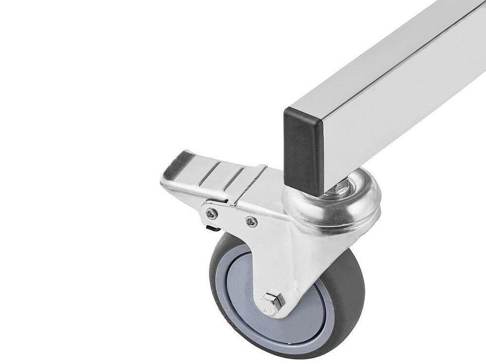 Obraz przedstawia metalowe koło z szarym bieżnikiem, zamocowane do chromowanego elementu konstrukcyjnego. Koło posiada mechanizm blokujący w postaci metalowej dźwigni.