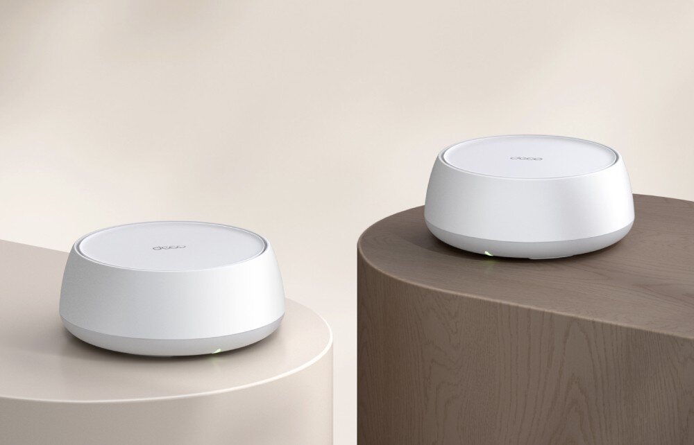 Router TP-LINK Deco BE22 Dwa okrągłe urządzenia sieciowe ustawione na dwóch nowoczesnych stolikach w jasnym wnętrzu, opis