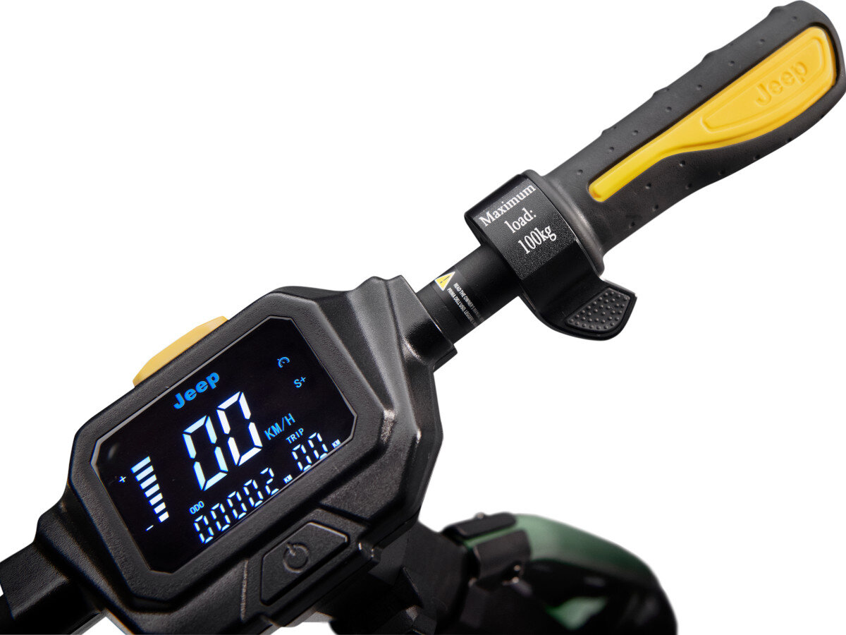Zbliżenie na kierownicę hulajnogi elektrycznej z wyświetlaczem pokazującym prędkość 00 KM/H i inne parametry. Na uchwycie widoczny jest napis \'Maximum load: 100kg\' oraz logo \'Jeep\'.