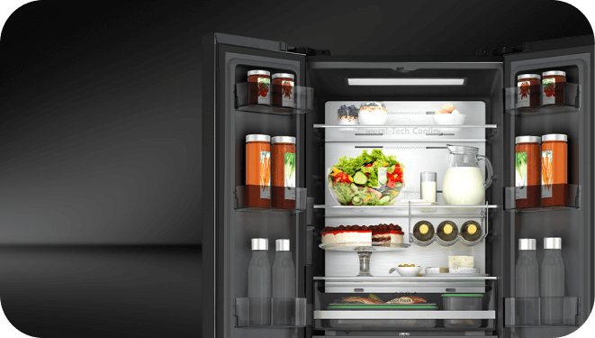 Otwarta lodówka z widocznymi półkami, na których znajdują się różne produkty spożywcze, takie jak sałatka, ciasto, jajka i napoje. Wewnątrz lodówki widoczny jest napis \'Metal Tech Cooling\'.