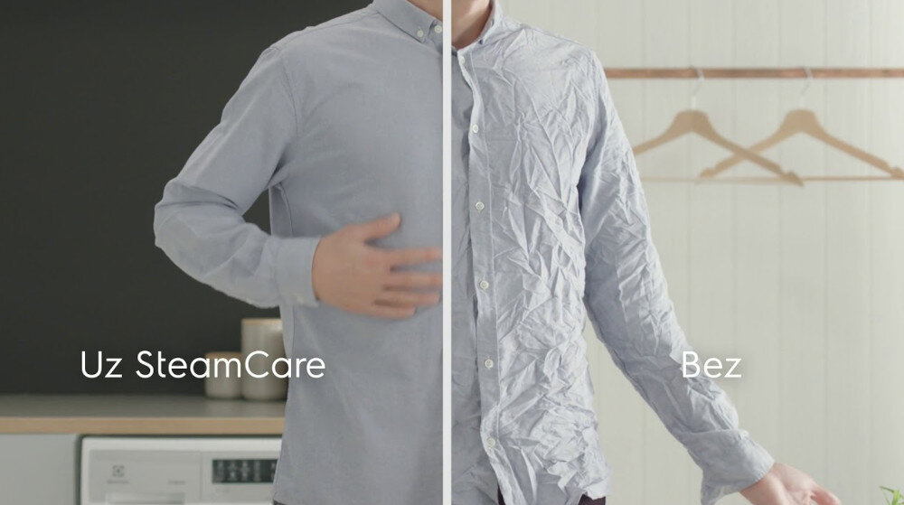 Obraz przedstawia porównanie dwóch koszul: po lewej stronie gładka koszula z napisem \'Uz SteamCare\', po prawej pognieciona koszula z napisem \'Bez\'. W tle widoczna jest pralka i kilka wieszaków.