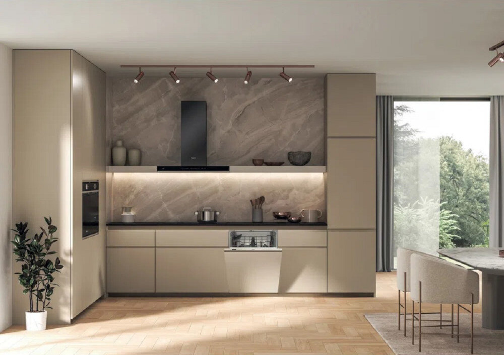 Nowoczesna kuchnia z zabudowaną zmywarką, otwartą szufladą i sprzętem kuchennym na blacie. W tle duże okno z widokiem na zieleń.