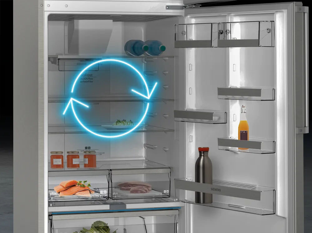 Otwarta lodówka z widocznymi półkami i produktami spożywczymi, takimi jak łosoś, mięso i napoje. Na drzwiach lodówki znajduje się logo \'SIEMENS\'.