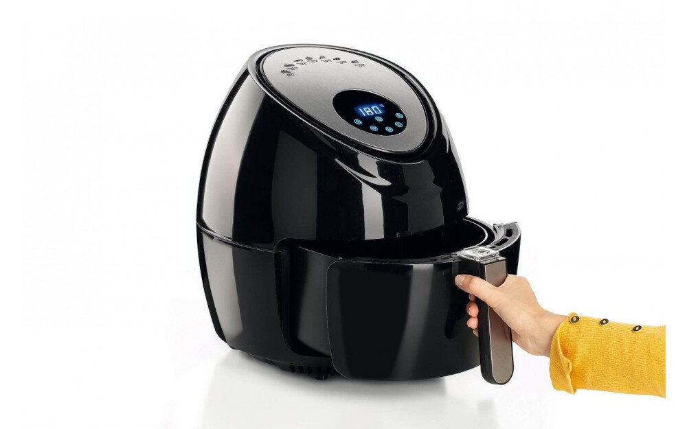 Czarna frytkownica beztłuszczowa z cyfrowym panelem sterowania, na którym widoczna jest temperatura 180°C. Osoba w żółtej bluzie trzyma uchwyt kosza frytkownicy.