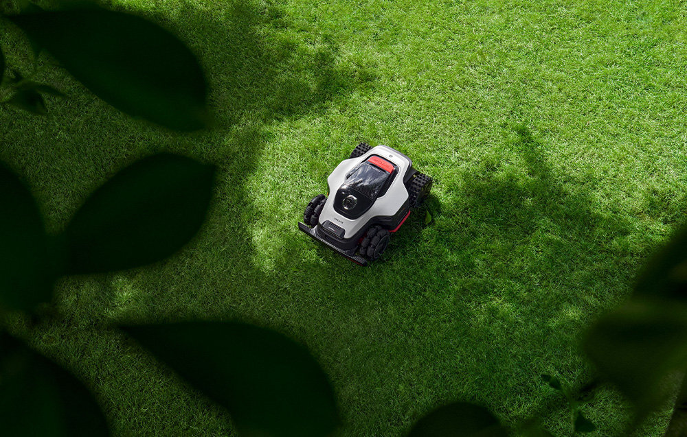 Robot koszący DREAME A3 AWD 1600 bez przewodu ograniczającego robot stoi w cieniu na trawniku widok z góry ochrona przed kradzieżą funkcje monitoringu ogrodu czujniki kontrolują pracę w różnych warunkach funkcja nadzoru stała kontrola otoczenia