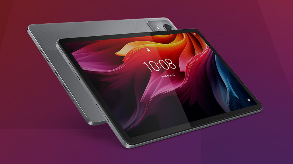Na obrazie widoczny jest szary tablet z dużym ekranem, na którym wyświetlany jest kolorowy motyw z godziną 10:08 i datą \'Wed, Mar 22\'. W tle widać tylną część tabletu z kamerą w rogu.