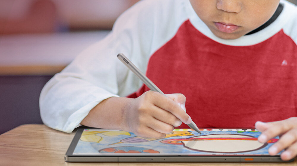 Dziecko rysuje na tablecie za pomocą rysika. Tablet wyświetla kolorowy obrazek.