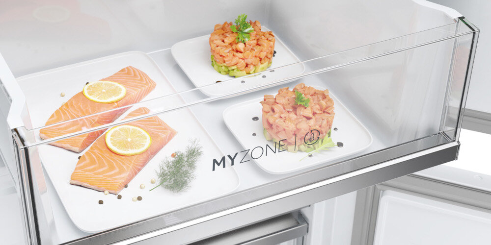 Wnętrze lodówki z przezroczystą szufladą oznaczoną napisem \'MY ZONE\'. W szufladzie znajdują się talerze z kawałkami łososia i tartarami z łososia udekorowanymi ziołami.