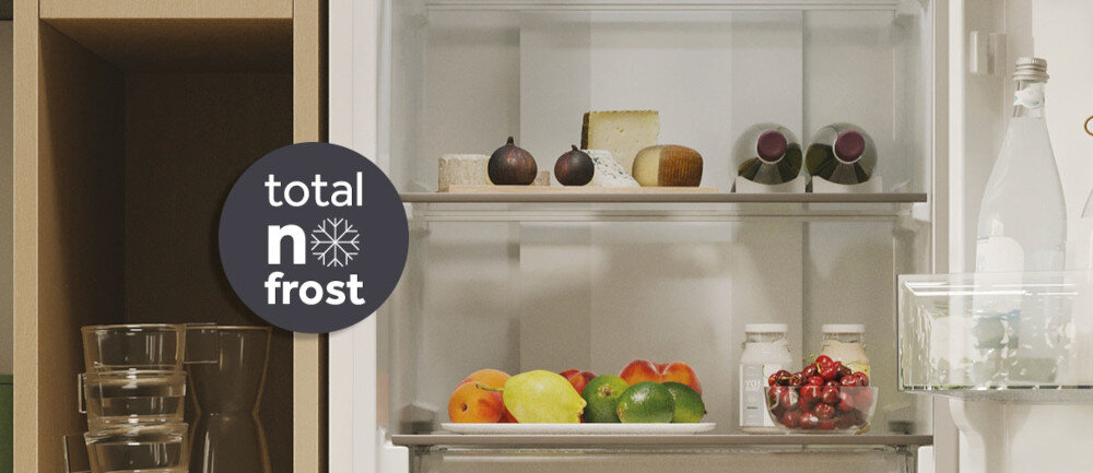 Wnętrze lodówki z widocznymi półkami, na których znajdują się owoce, sery i słoiki. Na drzwiach lodówki widoczny jest napis \'total no frost\'.
