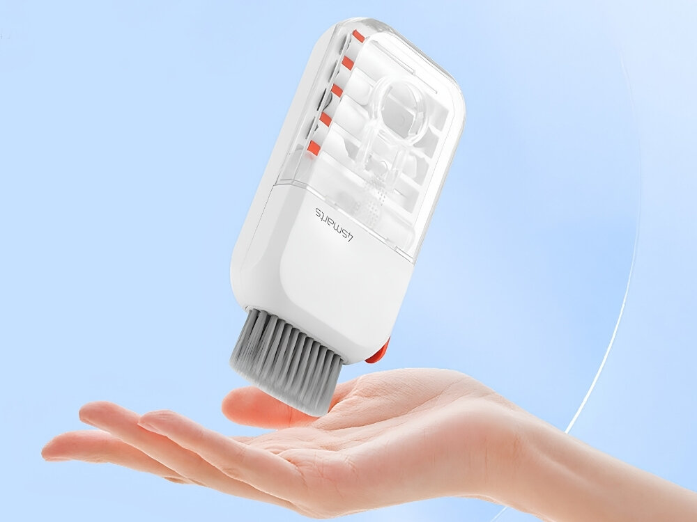 Na obrazie widoczny jest biały, wielofunkcyjny zestaw do czyszczenia elektroniki z logo \'4SMARTS\', trzymany nad otwartą dłonią. Urządzenie ma przezroczystą górną część i szarą szczotkę na dole.
