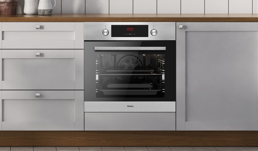 Piekarnik elektryczny w kolorze inox wbudowany w kuchenną zabudowę, z widocznym logo Amica na froncie. Na panelu sterowania wyświetlacz pokazuje \'0:00\'.