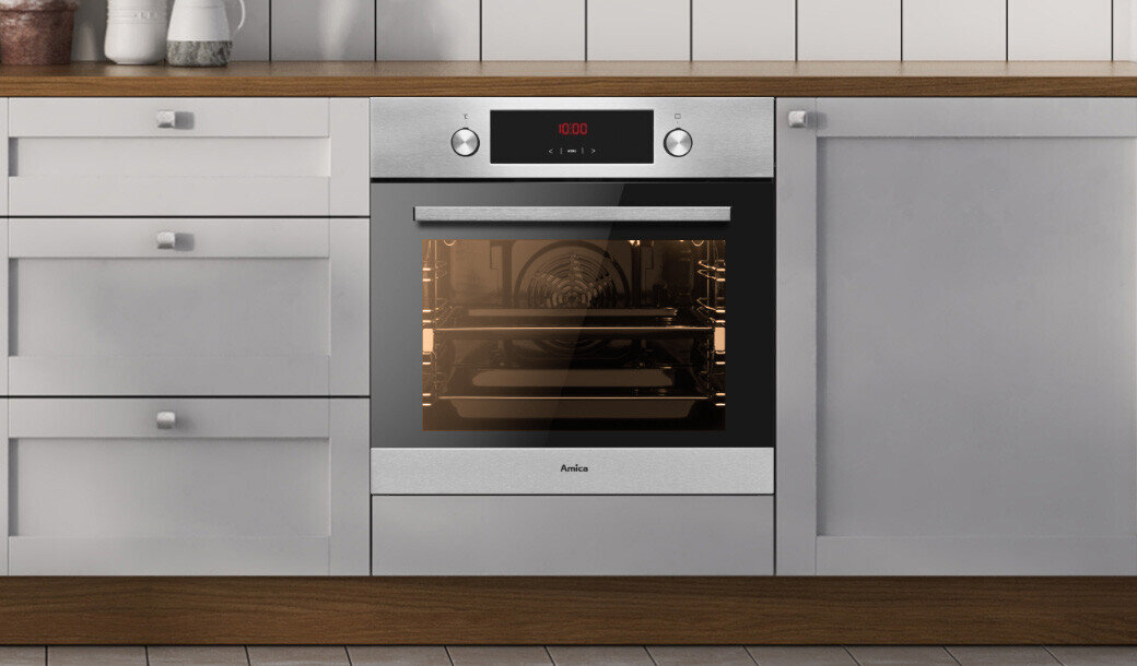 Piekarnik elektryczny w kolorze inox wbudowany w kuchenną zabudowę, z widocznym panelem sterowania i wyświetlaczem pokazującym \'12:00\'. Na drzwiach piekarnika znajduje się logo \'Amica\'.