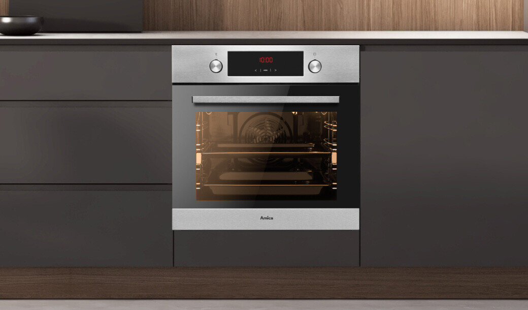 Na obrazie widoczny jest piekarnik w zabudowie kuchennej z wyświetlaczem pokazującym \'0:00\'. Piekarnik ma srebrny front z logo \'Amica\' i przeszklone drzwi, przez które widać wnętrze urządzenia.