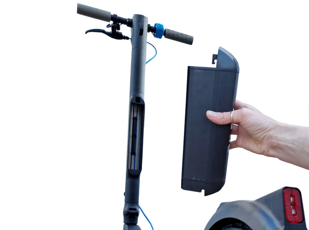 Na zdjęciu widać czarną hulajnogę elektryczną z wyjętym akumulatorem trzymanym w dłoni. Hulajnoga ma szare uchwyty i niebieski przewód przy kierownicy.