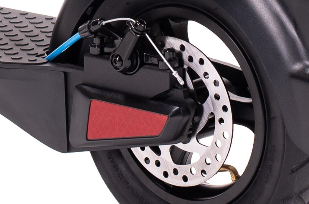 Zbliżenie na tylne koło hulajnogi elektrycznej z widocznym tarczowym hamulcem i czerwonym odblaskiem. Opona jest czarna, a elementy konstrukcyjne mają metaliczne i czarne wykończenie.