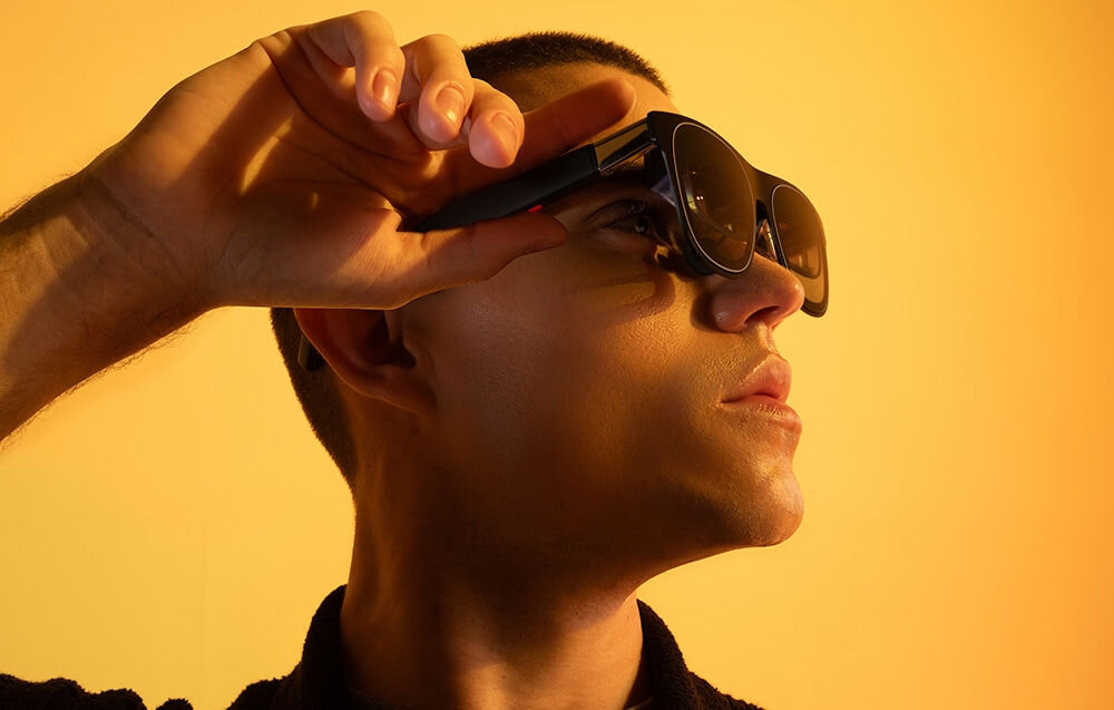 Okulary XREAL One Czarny prezentacja okularów założonych na mężczyźnie na zółtym tle procesor opóźnienie 3 ms płynne działanie usprawnienie przetwarzania obrazu