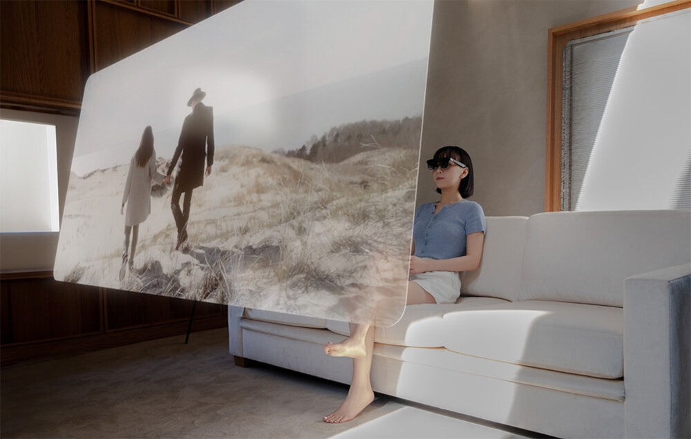 Okulary XREAL One Czarny prezentacja okularów podczas użytkowania przez kobietę siedzącą na jasnej kanapie w pokoju przed nią wirtualny ekran trzy tryby widzenia jasność czytelny obraz regulacja odległości między źrenicami