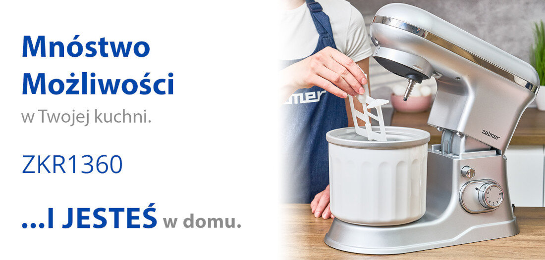 Obraz przedstawia srebrny robot planetarny z przystawką do lodów na blacie kuchennym. Po lewej stronie widoczny jest tekst: \'Mnóstwo Możliwości w Twojej kuchni. ZKR1360 ...I JESTEŚ w domu.\'