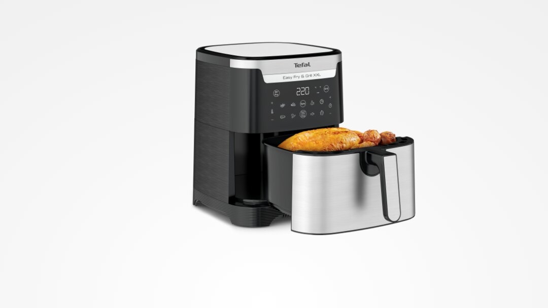 Na obrazie widoczna jest frytkownica beztłuszczowa z wyświetlaczem cyfrowym i otwartą szufladą, w której znajduje się pieczony kurczak. Na górnej części urządzenia widnieje logo \'Tefal\' oraz napis \'Easy Fry & Grill XXL\'.