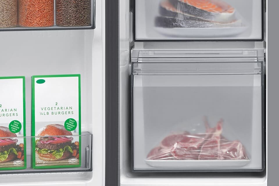 Wnętrze lodówki z widocznymi produktami spożywczymi. Po lewej stronie znajdują się opakowania z napisem \'2 VEGETARIAN 1/4 LB BURGERS\', a po prawej stronie w szufladach znajdują się kawałki mięsa i ryby.