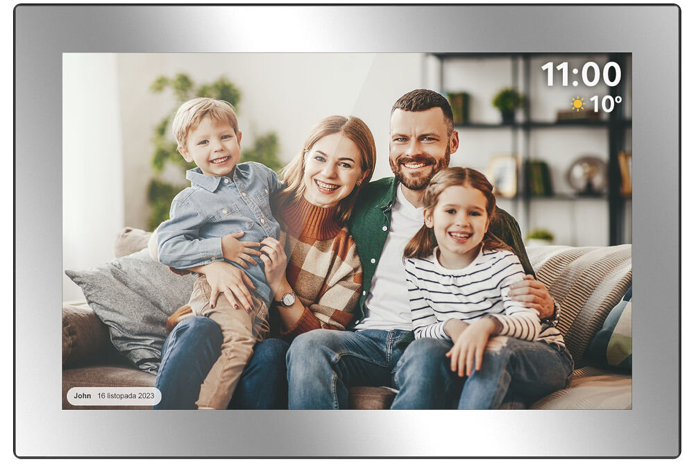 Srebrna ramka cyfrowa wyświetla zdjęcie czterech uśmiechniętych osób siedzących na kanapie. W prawym górnym rogu widoczny jest czas \'11:00\' i temperatura \'10°\', a w lewym dolnym rogu napis \'John 16 listopada 2023\'.