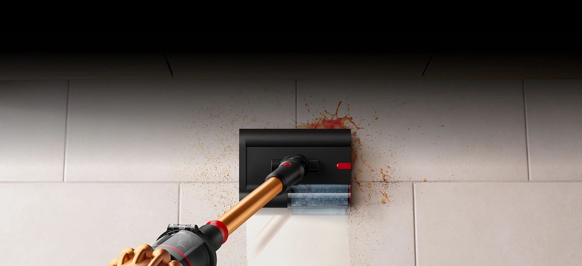 Odkurzacz z miedzianą rurą czyszczący podłogę z rozlaną cieczą i zabrudzeniami. Na podłodze widoczne są płytki oraz ślady brudu i cieczy.