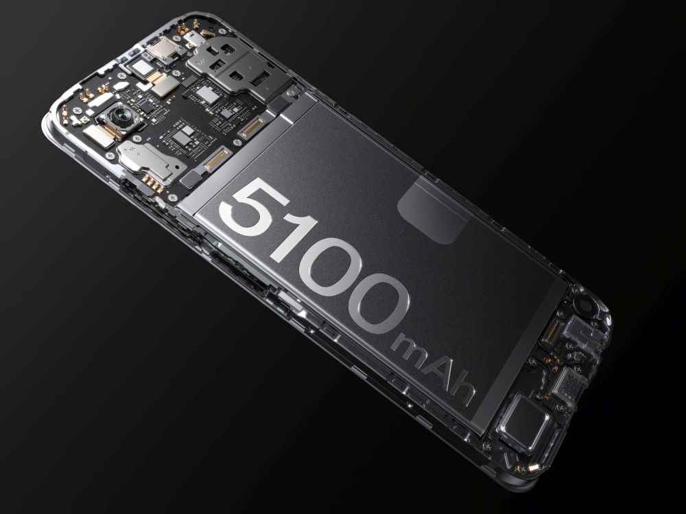 Obraz przedstawia wnętrze smartfona z widoczną baterią oznaczoną napisem \'5100 mAh\'. Widać również elementy elektroniczne i obwody na ciemnym tle.