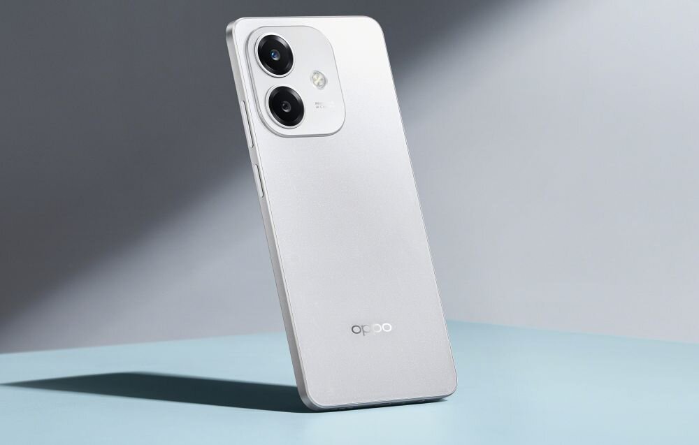 Na obrazie widoczny jest smartfon w kolorze srebrnym z dwoma dużymi obiektywami aparatu i logo \'oppo\' na obudowie. Telefon jest ustawiony pod kątem na jasnym tle.