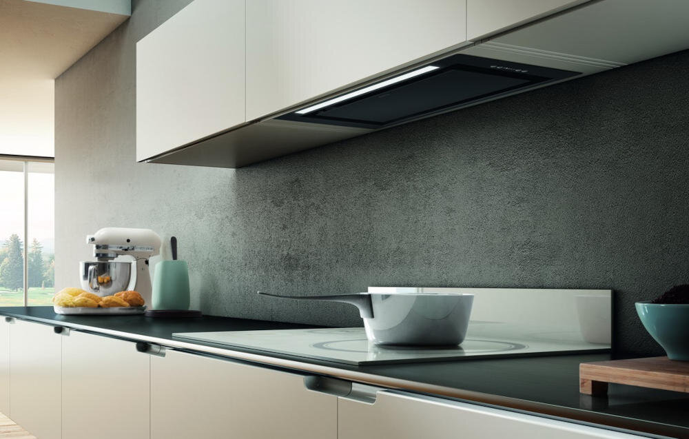 Kuchnia z nowoczesnym okapem wbudowanym w szafkę nad blatem. Na blacie znajduje się mikser, chleb oraz garnek na płycie grzewczej.