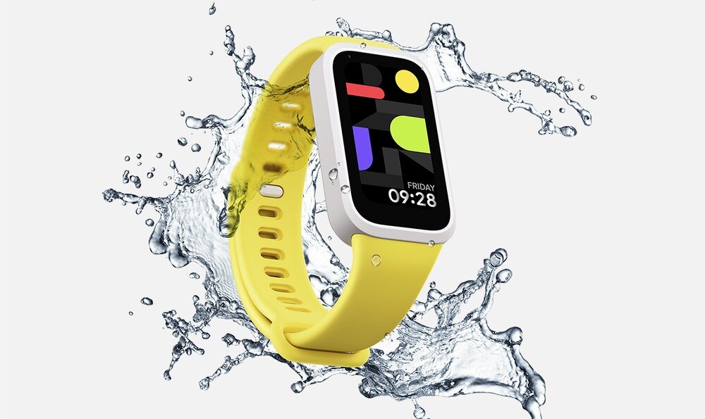 Smartband z żółtym paskiem i kolorowym wyświetlaczem, na którym widnieje godzina 09:28 i dzień \'FRIDAY\'. W tle widać rozpryskującą się wodę.