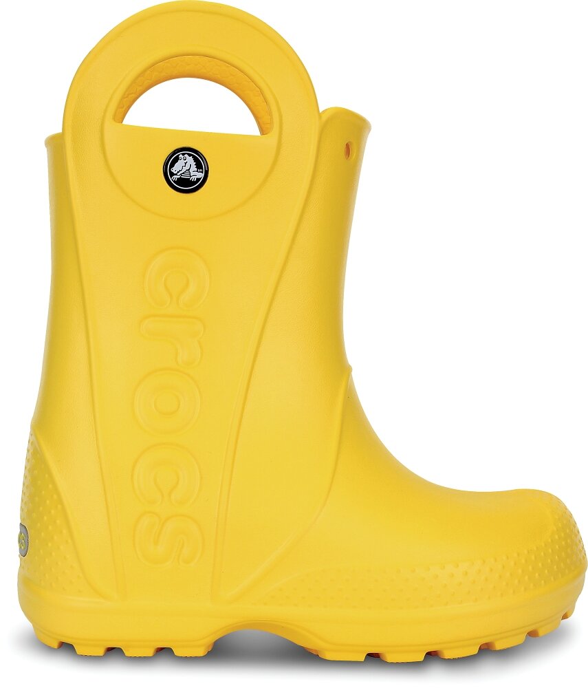 Żółty dziecięcy kalosz z dużym uchwytem na górze i napisem \'crocs\' wytłoczonym na boku. Na górze znajduje się okrągłe logo z białym krokodylem na czarnym tle.