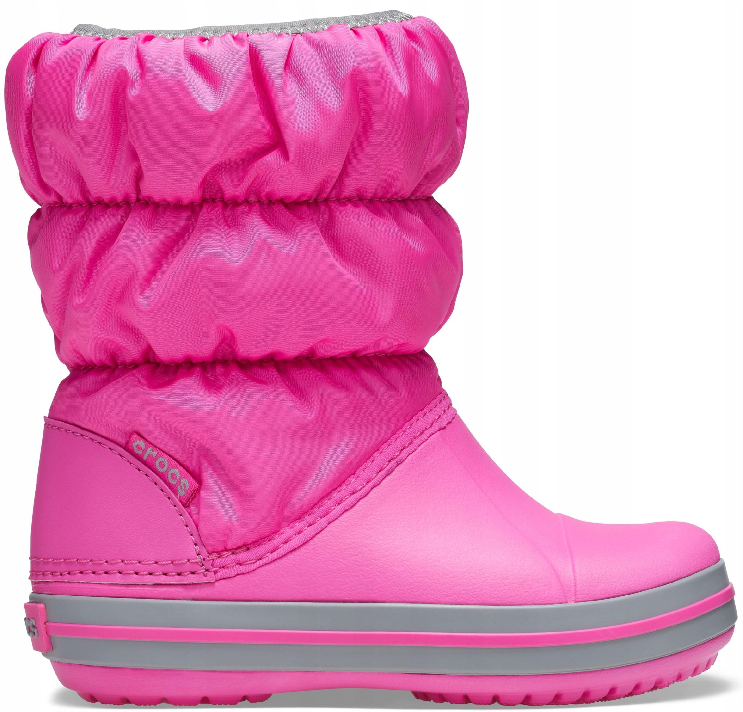 Różowy dziecięcy śniegowiec z marszczoną cholewką i szarymi paskami na podeszwie. Na boku widoczne jest logo \'crocs\'.
