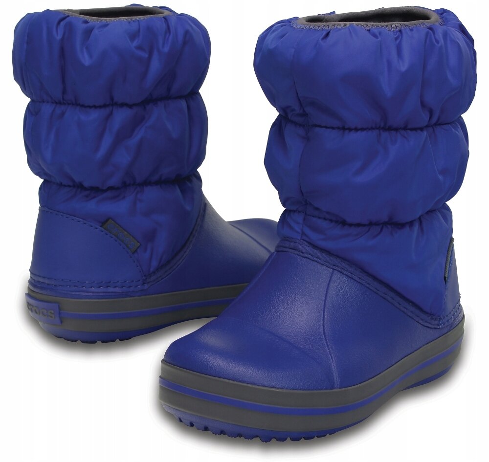 Na obrazie widoczne są niebieskie, ciepłe wodoodporne śniegowce zimowe z grubą podeszwą. Na jednym z butów znajduje się logo \'Crocs\'.