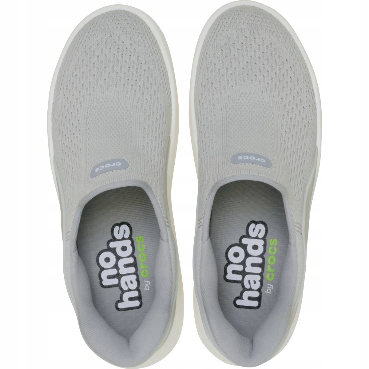 Para szarych butów sportowych typu slip-on z widocznym napisem \'no hands by crocs\' wewnątrz. Na górze butów znajduje się logo \'crocs\'.