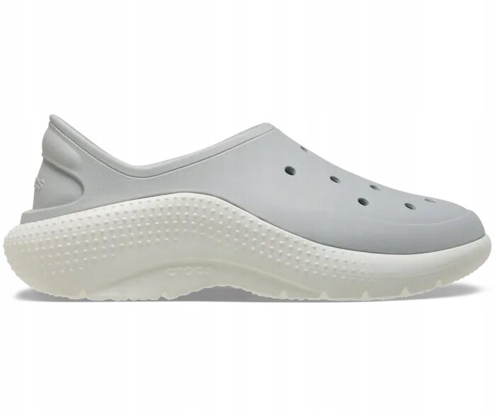 Szare, wsuwane buty sportowe z perforacjami na górze i białą, teksturowaną podeszwą. Na podeszwie widoczne jest logo \'crocs\'.