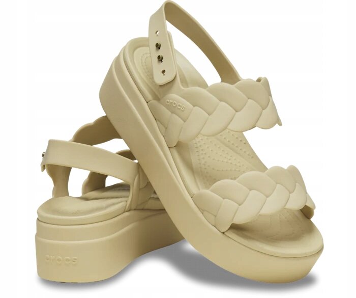 Beżowe sandały na platformie z plecionym paskiem i regulowanym zapięciem. Na boku widoczne jest logo \'crocs\'.