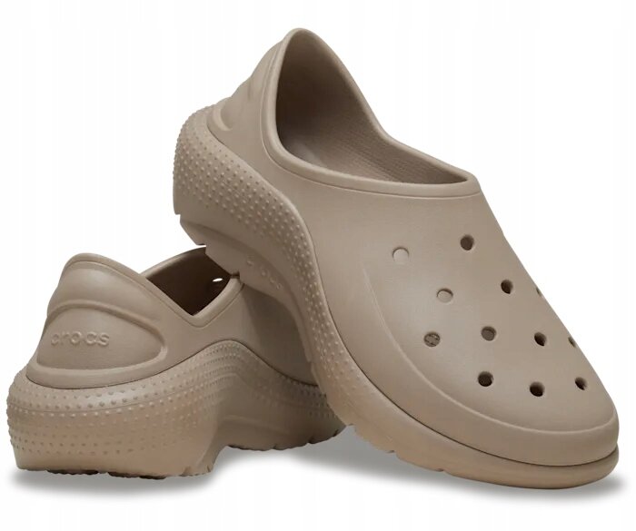 Dwa beżowe buty wsuwane z otworami na górze i teksturą na podeszwie. Na jednym z butów widoczne jest logo \'crocs\'.