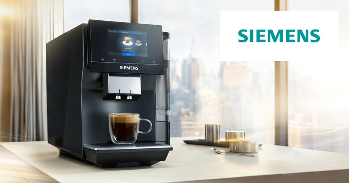 Na blacie stoi czarny ekspres do kawy z filiżanką kawy pod wylewką. W tle widoczne jest logo \'SIEMENS\'.