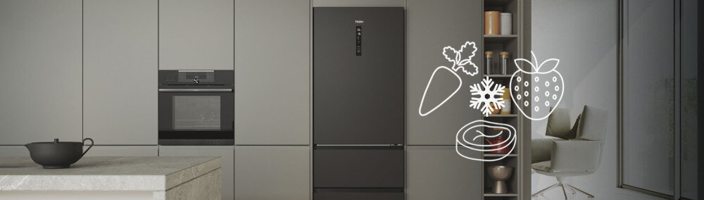 Czarna lodówka z logo \'Haier\' stoi w nowoczesnej kuchni, obok niej znajdują się ikony przedstawiające marchewkę, płatek śniegu, truskawkę i kawałek mięsa. W tle widać szafki kuchenne, piekarnik oraz półki z naczyniami.